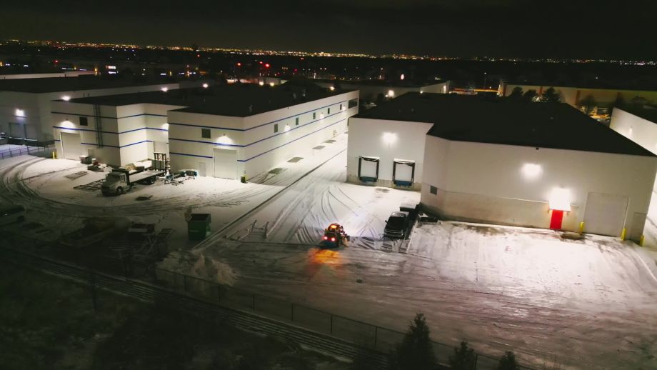 A team of Black Swan Landscaping workers operating a snow blower on a commercial property in Vaughan, Ontario, demonstrating professional snow management during a heavy snowstorm.